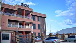 A multi-story hotel with a balcony on the second floor, a sign reading "La Star Hotel," and a gated entrance with cars parked in front. - La Stanar Hotel (Dodoma)