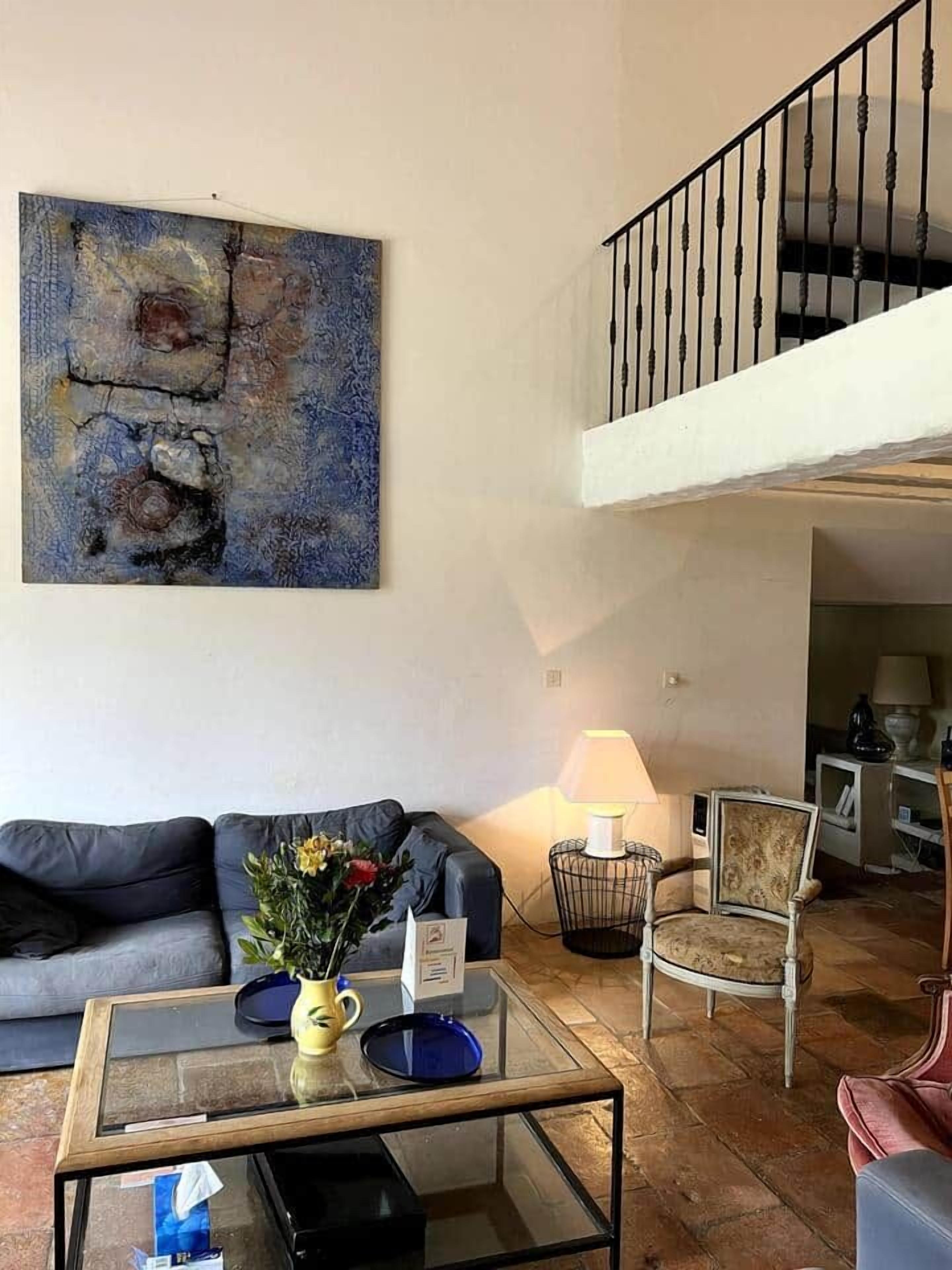 A living room with a sofa, a coffee table, a chair, a lamp, and a staircase.