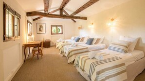 A room with three beds, a desk, and a chair.