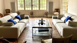 A living room with two sofas, a coffee table, and a large window with a view of greenery.