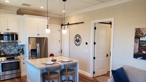 A modern kitchen with white cabinets, stainless steel appliances, and a central island with bar stools. - Romantic 1 Bedroom Villa Overlooking the Vineyards with INCREDIBLE VIEWS! (Temecula)