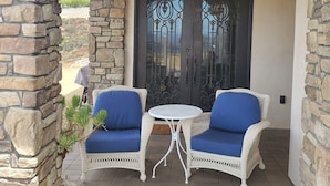A stone archway leading to a patio with two wicker chairs and a small table. - Romantic 1 Bedroom Villa Overlooking the Vineyards with INCREDIBLE VIEWS! (Temecula)