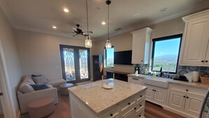 A modern kitchen with white cabinetry, a large island, and a view of the outdoors. - Romantic 1 Bedroom Villa Overlooking the Vineyards with INCREDIBLE VIEWS! (Temecula)