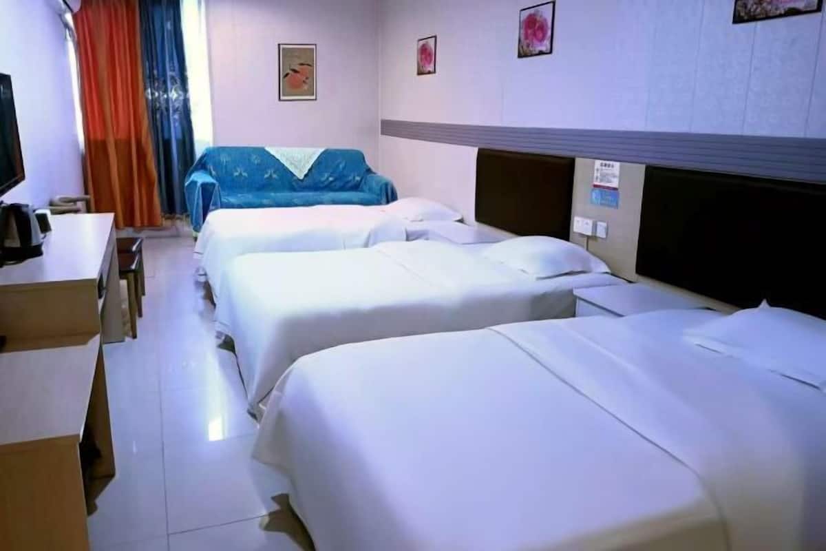 A hotel room with two beds, a desk, a chair, and a television.