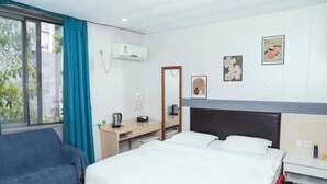 A hotel room with a bed, a desk, a chair, a mirror, and a shoe rack. - Yunlin Hotel (Guangzhou)