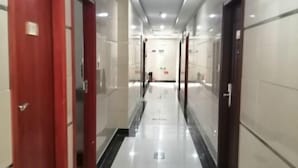 A hallway with a shiny floor, red doors, and a sign indicating a direction. - Yunlin Hotel (Guangzhou)