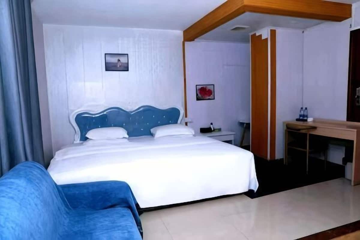 A hotel room with a bed, a desk, and a chair.