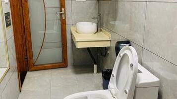 A bathroom with a toilet, a sink, and a glass shower enclosure.