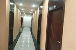 Un pasillo con puertas a ambos lados, un cartel sobre una puerta y suelo de baldosas.