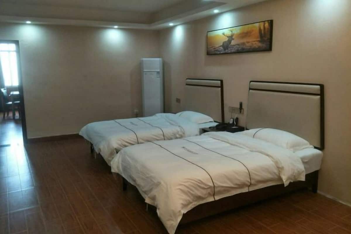 Habitación de hotel con dos camas, un cuadro en la pared y un refrigerador.