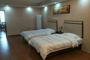 A hotel room with two beds, a painting on the wall, and a refrigerator. - Luanchuan Friendship Business Hotel (Suichuan)