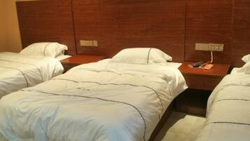 Ett hotellrum med två separata sängar, en sänggavel i trä, sängbord och en kontrollpanel på väggen.