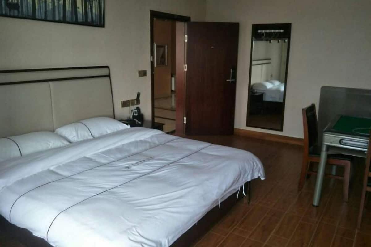 Una habitación de hotel con una cama grande, un escritorio y un espejo.