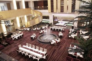 A spacious lobby with a central fountain, multiple seating areas, and a curved balcony. - Peninsula Hotel (Xiangshan)