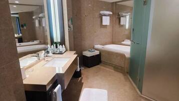 A modern bathroom with two sinks, a bathtub, a shower, and a large mirror.