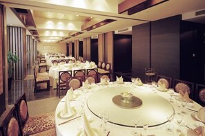 Un comedor formal con mesas redondas dispuestas para varios invitados, con un elemento decorativo central.