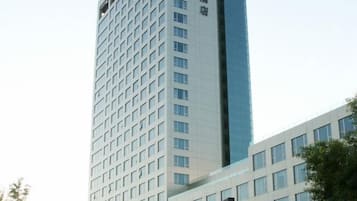 Een hoog gebouw met een gegrilde gevel en een glazen reflecterende partij.