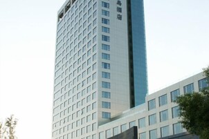 Un edificio de gran altura con fachada enrejada y sección de vidrio reflectante.
