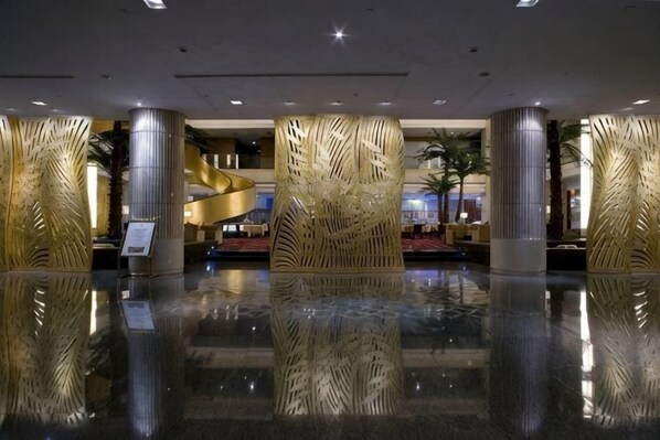 A lobby with reflective flooring, a central spiral staircase, and decorative pillars. - Peninsula Hotel (Xiangshan)
