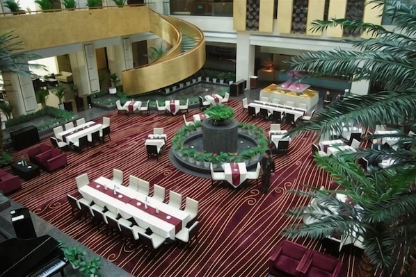 A hotel lobby with multiple seating areas, a central fountain, and a curved staircase. - Peninsula Hotel (Xiangshan)