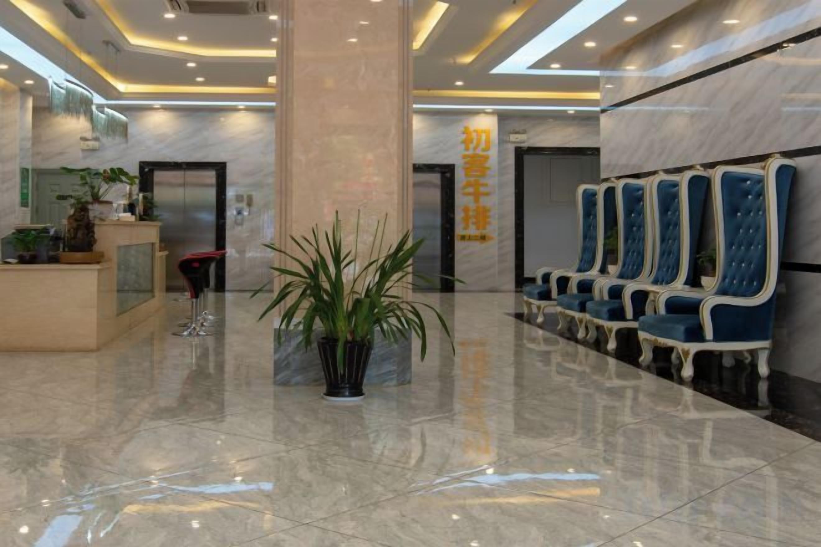 A hotel lobby with a reception desk, seating area, and a large pillar.