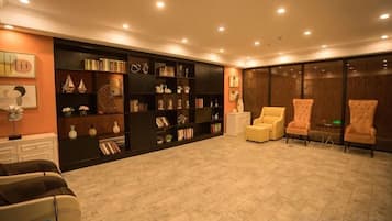 Una habitación amplia con una gran estantería, dos sillones y una pequeña mesa.