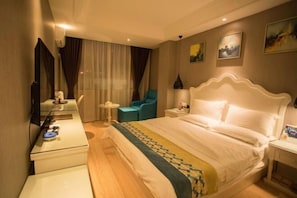A hotel room with a large bed, a desk, a chair, and a small table.