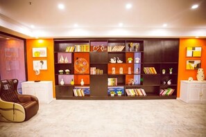 Ein Zimmer mit einem großen Bücherregal, einem weißen Schrank und einem braunen Sessel.