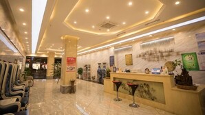 Eine Hotelhalle mit Empfangsschalter, Sitzgelegenheiten und einer großen Säule.