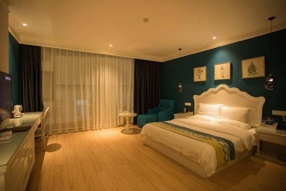 Une chambre d’hôtel avec un grand lit, un bureau avec une chaise, une petite table et un téléviseur.