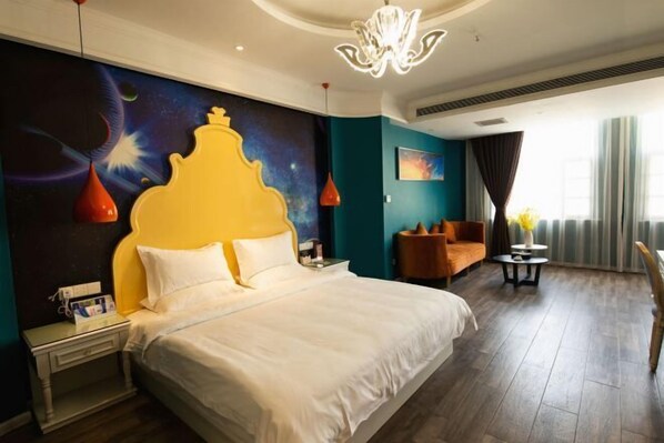Habitación de hotel con una cama grande, una mesita de noche, un espacio de descanso y vistas al exterior.