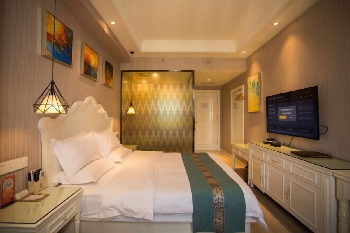Une chambre d’hôtel avec un lit, une table de chevet, une télévision et des œuvres d’art accrochées aux murs.
