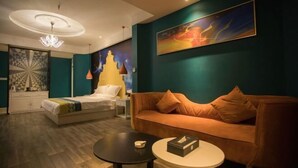 Ein modernes Hotelzimmer mit einem Bett, einer Couch, einem runden Tisch und einem Bild an der Wand.