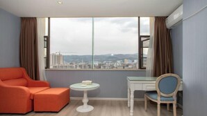 Ein Zimmer mit Blick auf die Stadt, inklusive einer Couch, eines kleinen Tisches und einem Sessel.