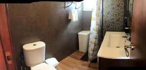 Een badkamer met toilet, wastafel en douchegordijn.