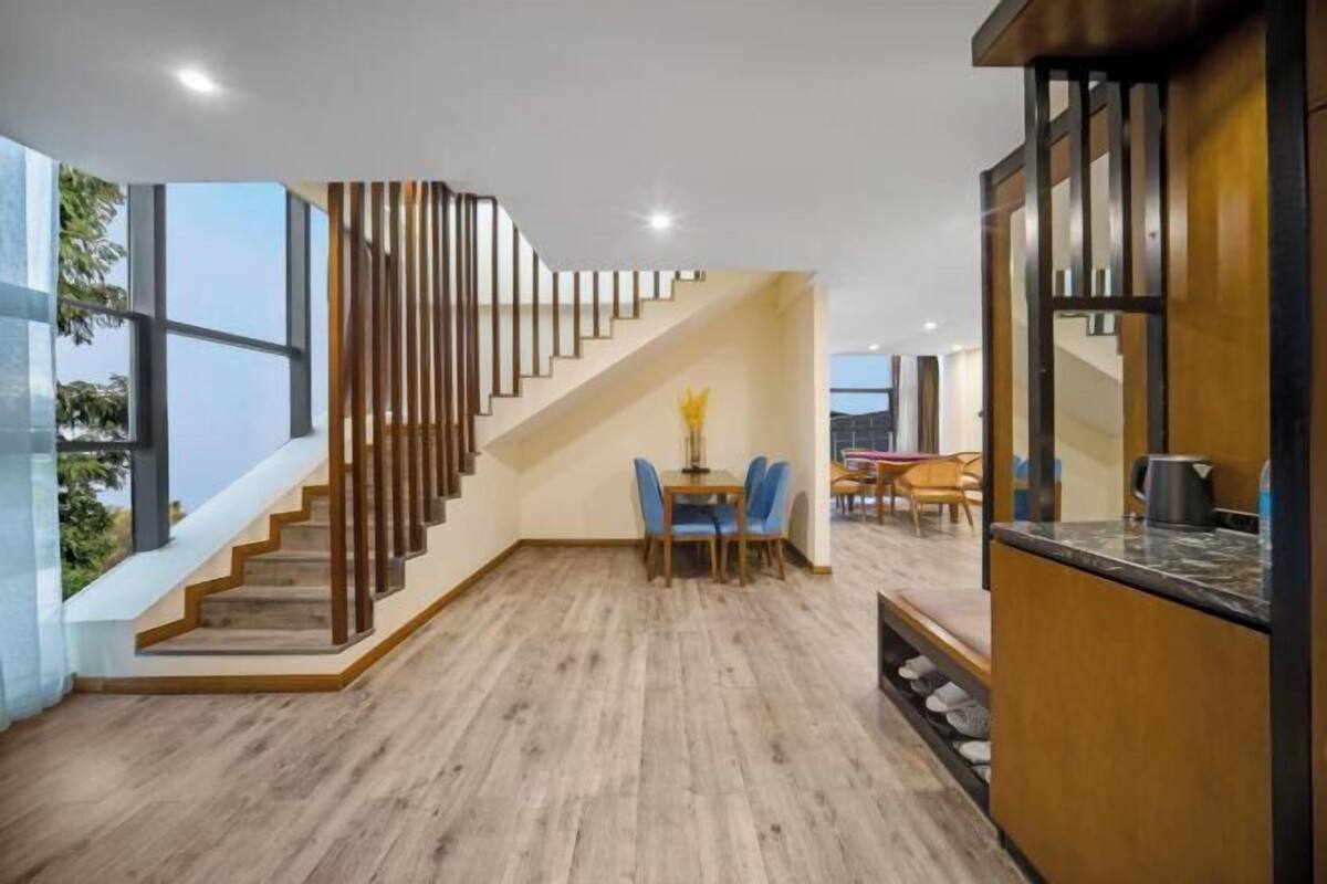 Een modern interieur met een houten trap, een eethoek met blauwe stoelen en een keuken met een marmeren aanrecht.