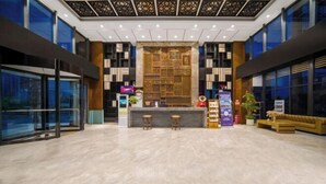 Un hall d’entrée moderne doté d’un comptoir de réception, d’un espace salon et de grandes fenêtres.