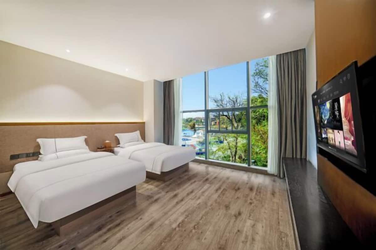 Een hotelkamer met twee bedden, een groot raam met uitzicht en een flatscreen televisie.