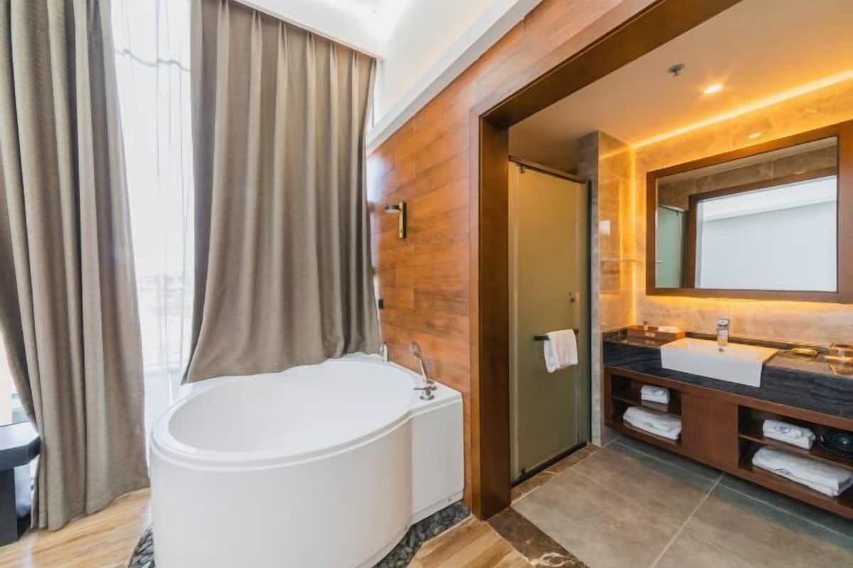 Een moderne badkamer met een vrijstaand bad, een grote spiegel en een wastafelmeubel met een wastafel en handdoekopbergruimte.