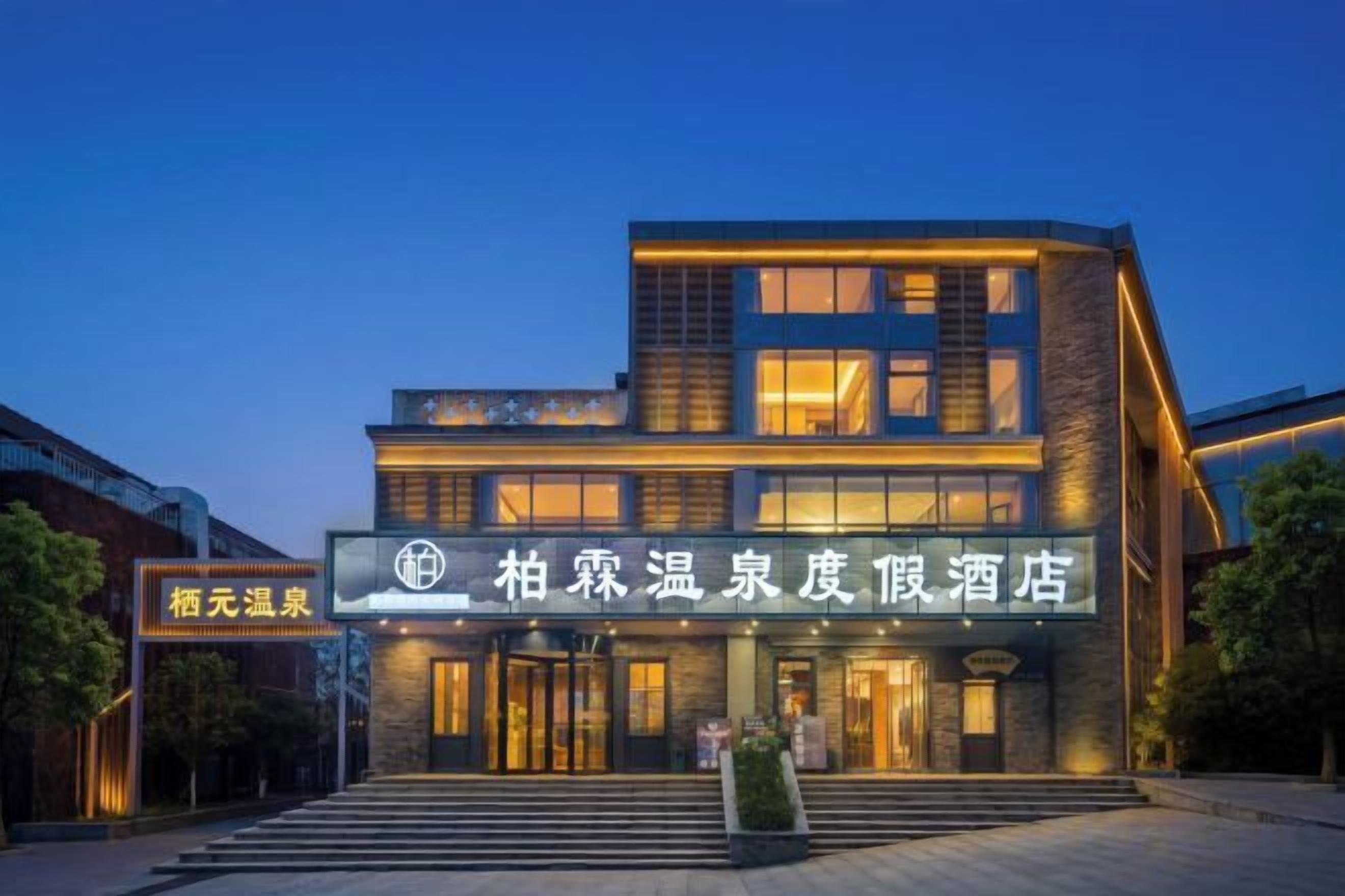 A modern hotel with a multi-story structure, illuminated entrance, and a signboard with Chinese characters.