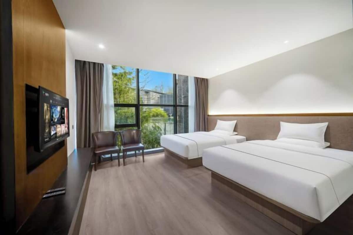 Een hotelkamer met twee bedden, een televisie, een stoel en een groot raam.