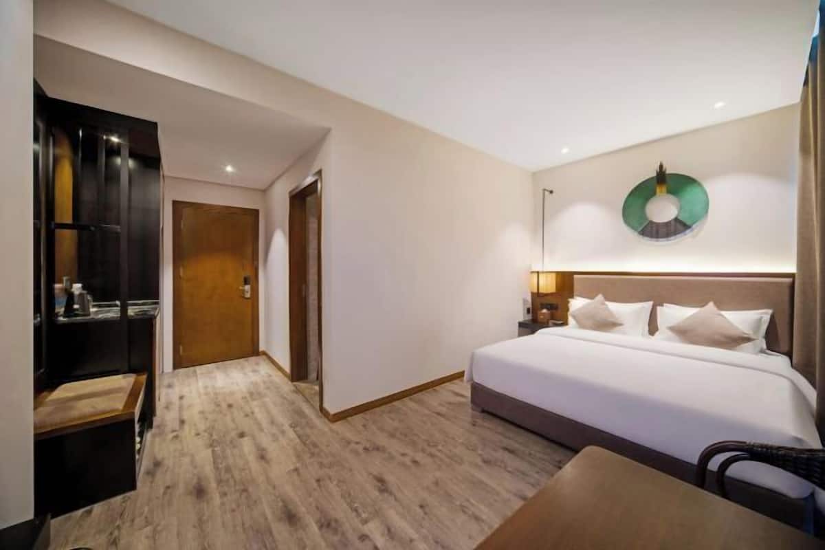Een hotelkamer met een bed, nachtkastje, lamp en een rond decoratie aan de muur.