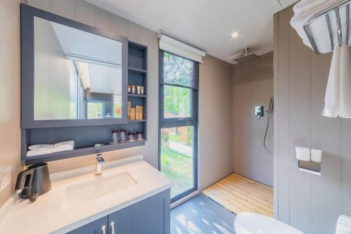 Een moderne badkamer met een grote spiegel, een wastafel en een douchecabine.