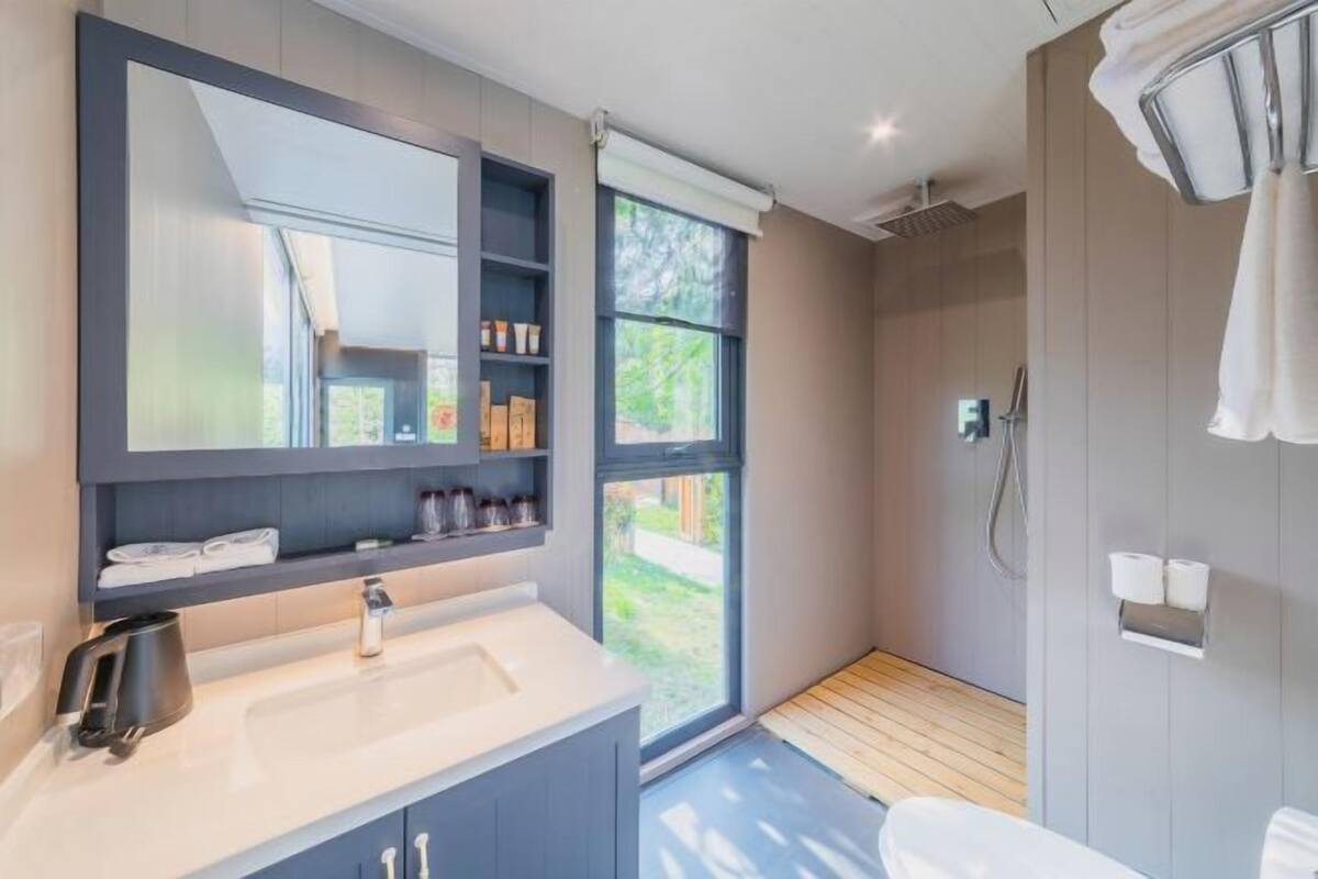Un baño moderno con un espejo grande, un lavabo y una zona de ducha.