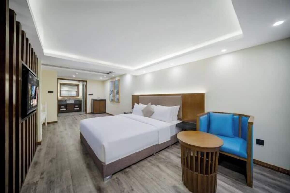 Een hotelkamer met een bed, een zithoek, een televisie en een bureau.