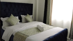 A neatly made bed with a dark headboard, white linens, and a rolled towel. - Nanyuki One Bedroom Apartment (Nanyuki)