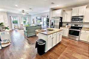A modern kitchen with white cabinets, stainless steel appliances, and a central island.