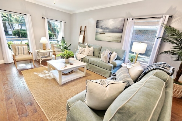 A living room with a sofa, coffee table, and a painting on the wall.