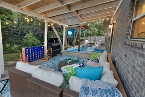 An outdoor patio with a barbecue, seating area, and string lights.