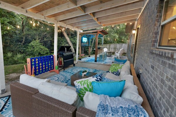 An outdoor patio with a barbecue, seating area, and string lights.
